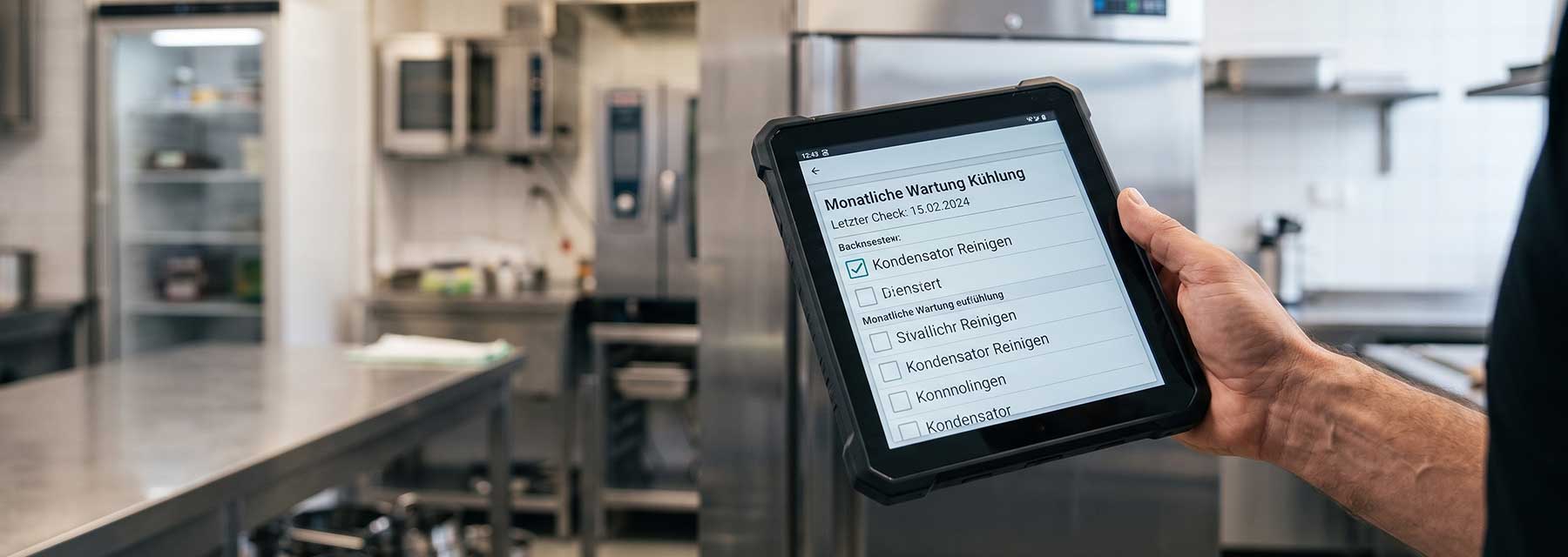 Tablet mit digitaler Wartungscheckliste 'Monatliche Wartung Kühlung' inklusive abgehaktem Punkt Kondensator reinigen in einer Gastroküche